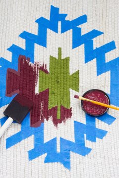 making use of a foam brush to color a kilim design onto a rug